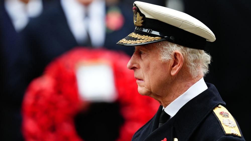 King Charles, in his navy uniform, looks sombrely ahead