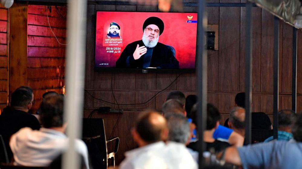 People watch Hezbollah Secretary-General Hassan Nasrallah delivering a televised speech at a coffee shop in the southern suburb of Beirut, Lebanon, 25 August 2024.