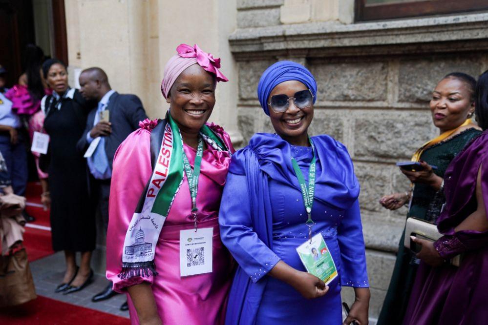 Guests, wearing pink and blue dresses, arrive at the State of the Nation Address red carpet and pose for a photograph outside of City Hall in Cape Town, South Africa.