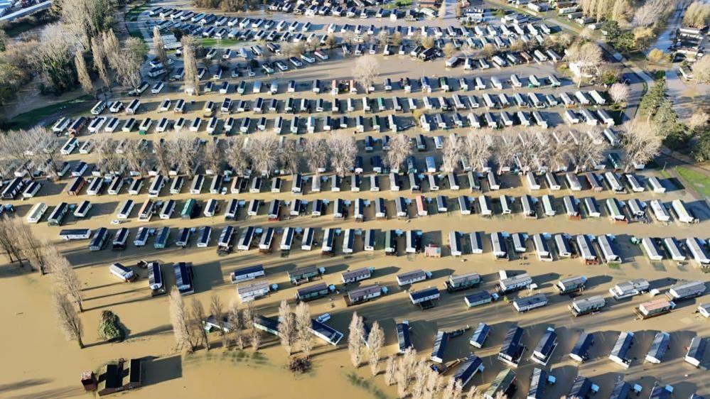 A drone shot showing rows multiple layers of rectangular properties partially submerged in brown water.