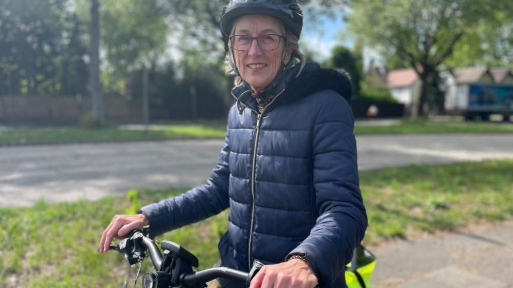 An image of Katherine, a resident of Wollaton. She is sat on her bicycle, wearing a helmet.