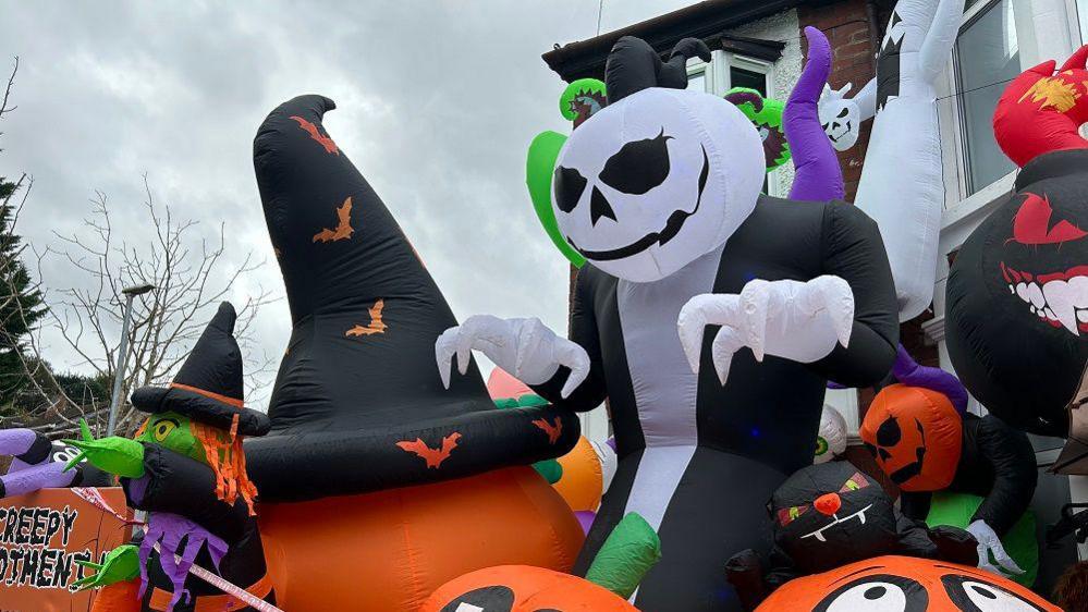 A closer look at the big inflatable decorations - the large grim reaper is in black & white with a pumpkin-style head and is surrounded by big pumpkins, including one with a tall witches hat.