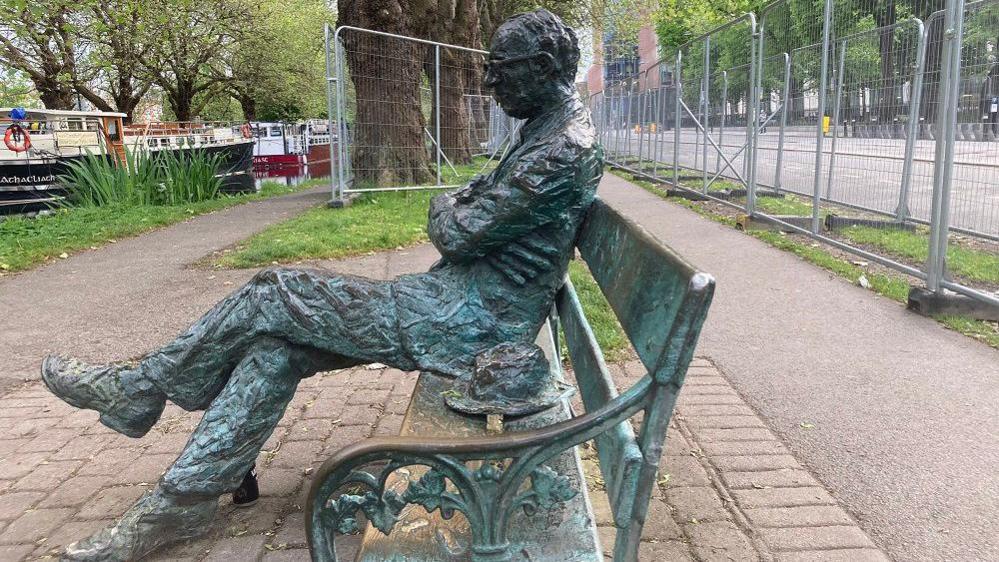 Patrick Kavanagh statue with steel barriers in background