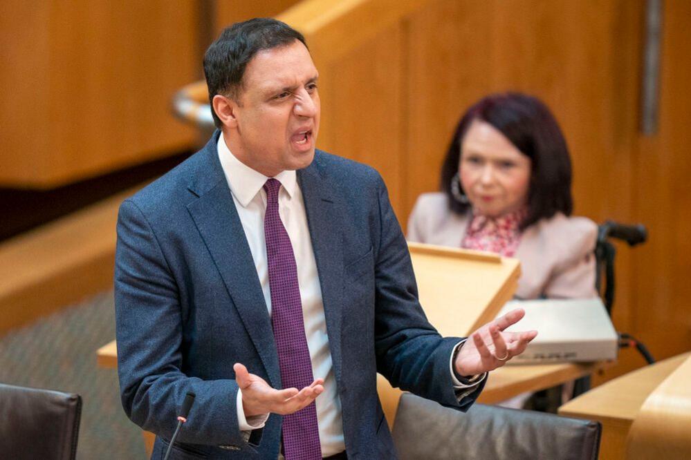 Anas Sarwar speaking in the Scottish parliament. He is wearing a dark blue suit and a purple tie
