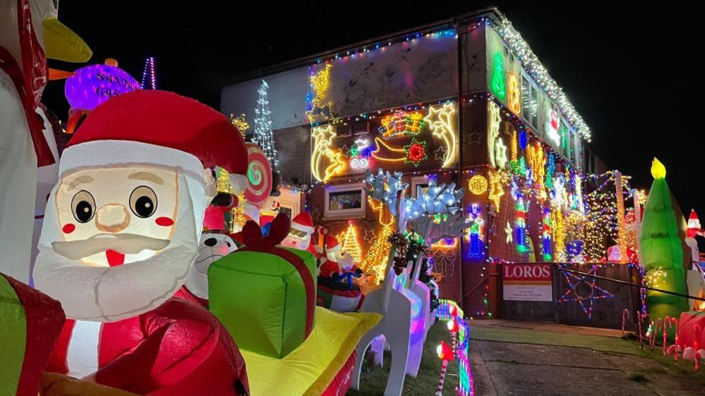 A view of an inflatable Santa in a sleigh, with the Hand Avenue Christmas display in the background.