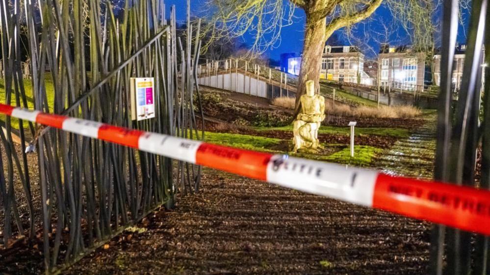 Red and white police tape crosses a gate before a statue in front of a tree outside Drents Museum in Assen, the Netherlands