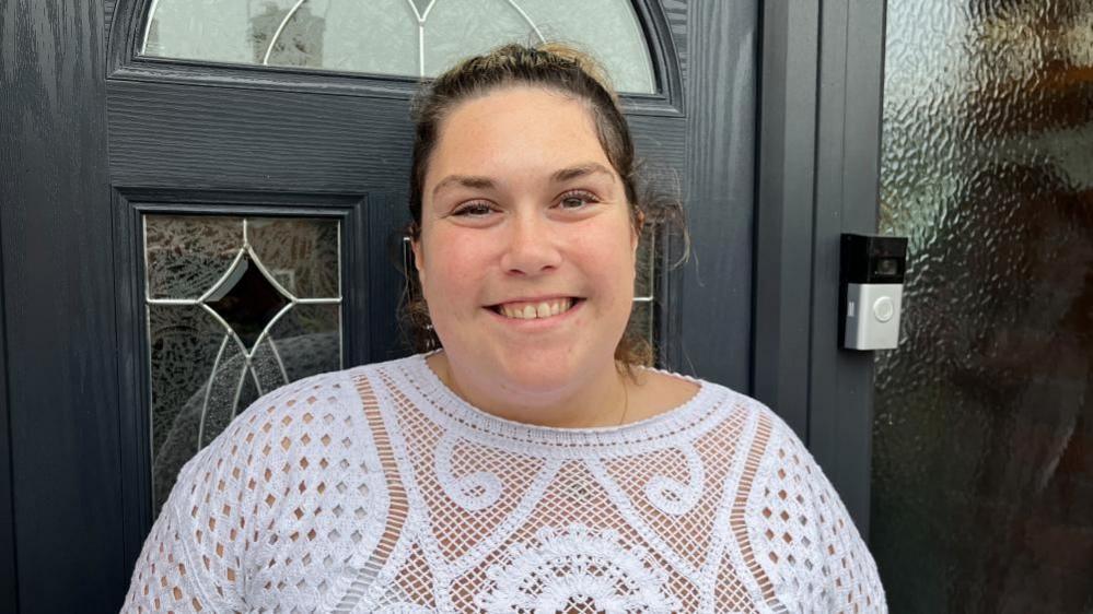 A photo of a woman, smiling, outside the door of her home in Radcliffe-on-Trent.