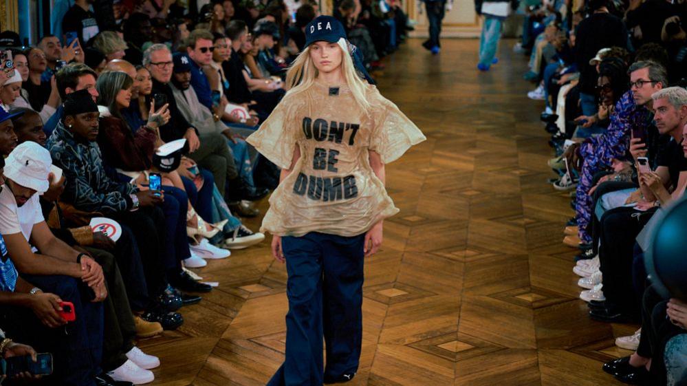 Model wearing shirt saying "Don't Be Dumb" walks the runway at Paris Fashion Week