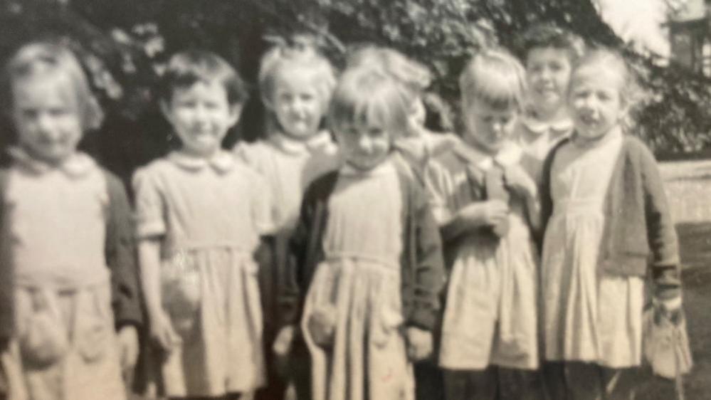 A black and white picture of young girls in school dresses.