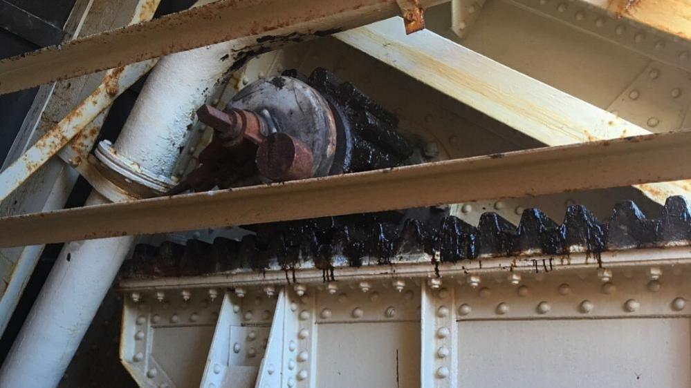 A toothed rack and geared pinion wheel, part of the original mechanism of Haven Bridge, pictured prior to upgrade works in 2018. Pipes and plates, held together with riveted ribs, can also be seen