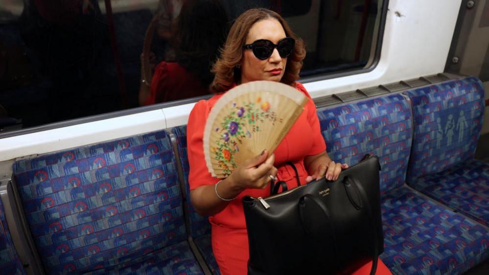 A woman on the London Underground with a fan