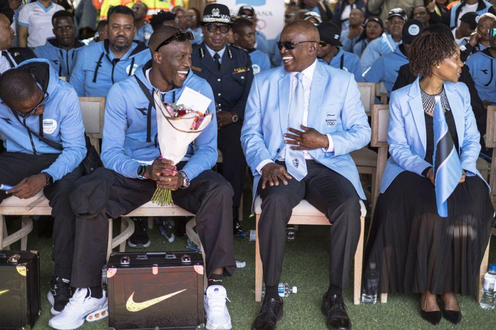 Botswana President Mokgweetsi Masisi (2nd R) share a laugh with Olympic gold medallist Letsile Tebogo (2nd L) at the beginning of a welcoming ceremony after winning the men's 200m athletics event during the Paris 2024 Olympic Games, at the Sir Seretse Khama International Airport in Gaborone on August 13, 2024. 