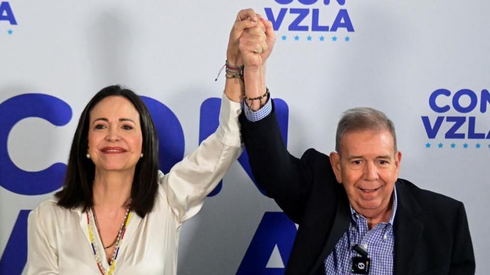 Venezuelan opposition leader Maria Corina Machado and opposition presidential candidate Edmundo Gonzalez raise their hands during a press conference following the announcement by the National Electoral Council that Venezuela's President Nicolas Maduro won the presidential election, in Caracas, Venezuela, July 29, 2024.