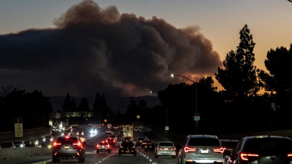 Smoke rises over the hills from the Palisades Fire