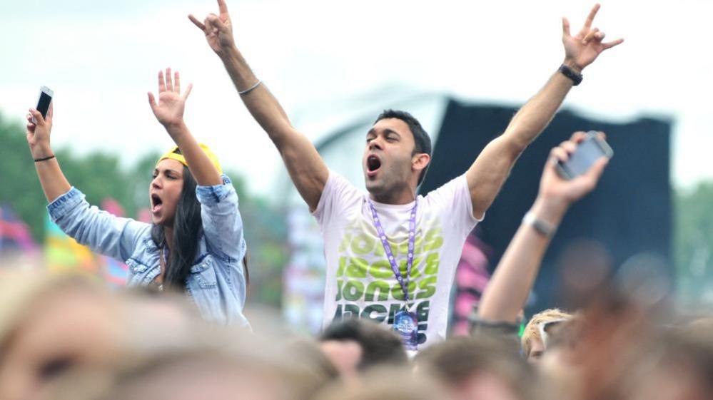 Man and woman raising hands in air