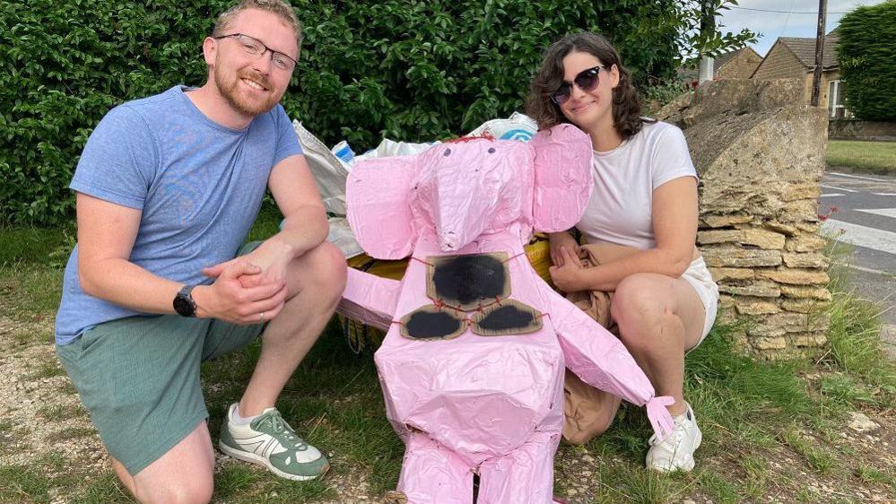 A couple kneel either side of an amateur model of a pink clanger