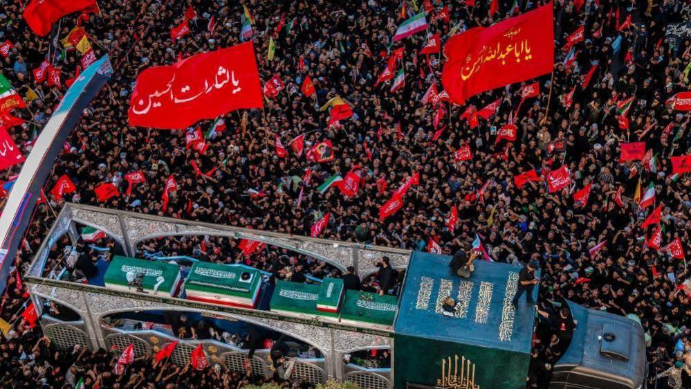 الأعلام الحمراء والأعداد الكبيرة من الناس في جنازة خامنئي في مشهد