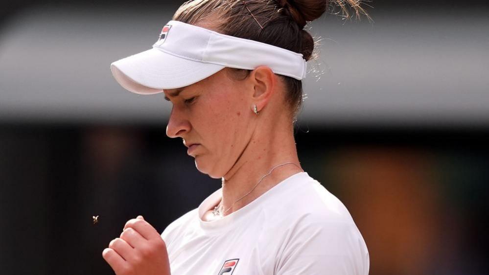 Tennis player Barbora Krejcikova looking down at a flying ant during a match at Wimbledon