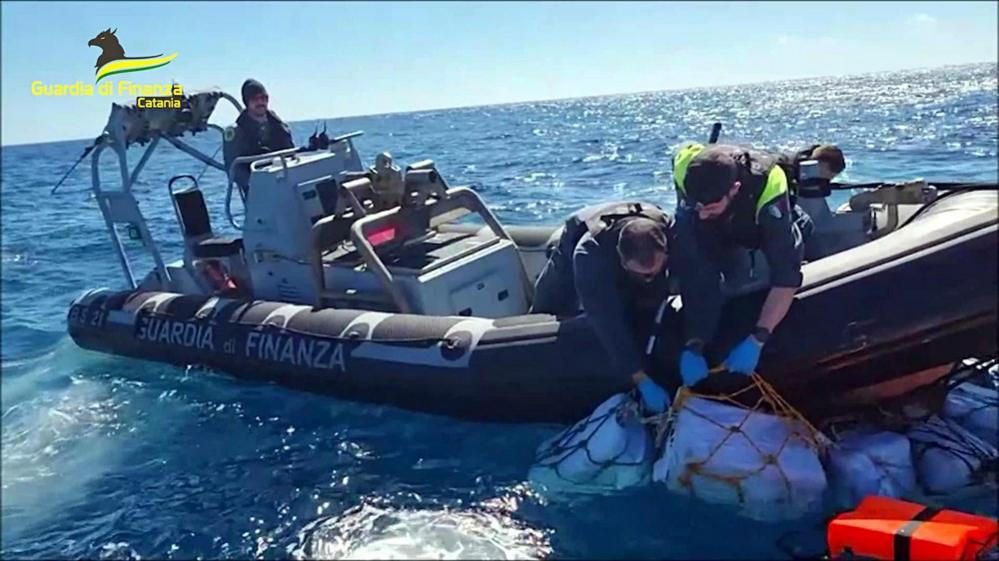 Police hauling packages into a boat from the sea