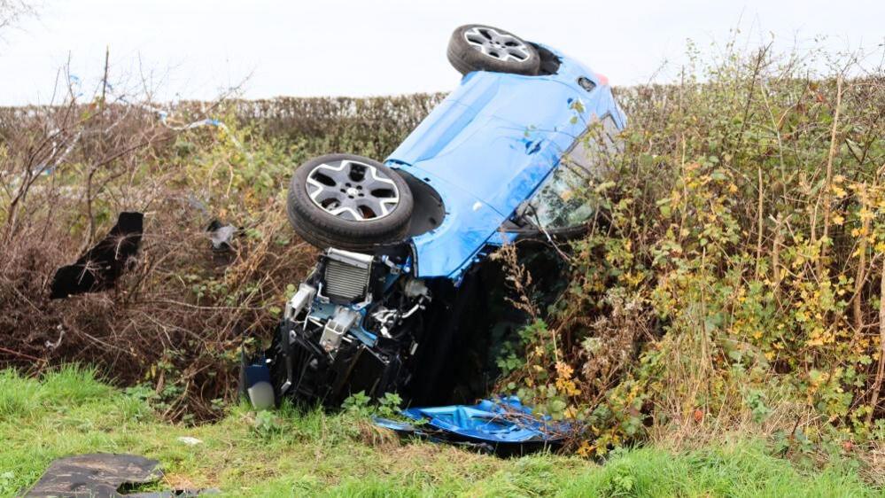 A crashed car in a ditch, viewed from the front