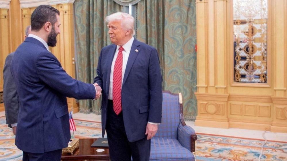 Sharaa and Trump shake hands in an opulent palace meeting room