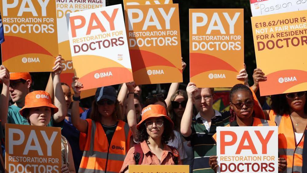 Image shows doctors on strike holding placards outside St. Thomas's hospital in London on 25 July 2025