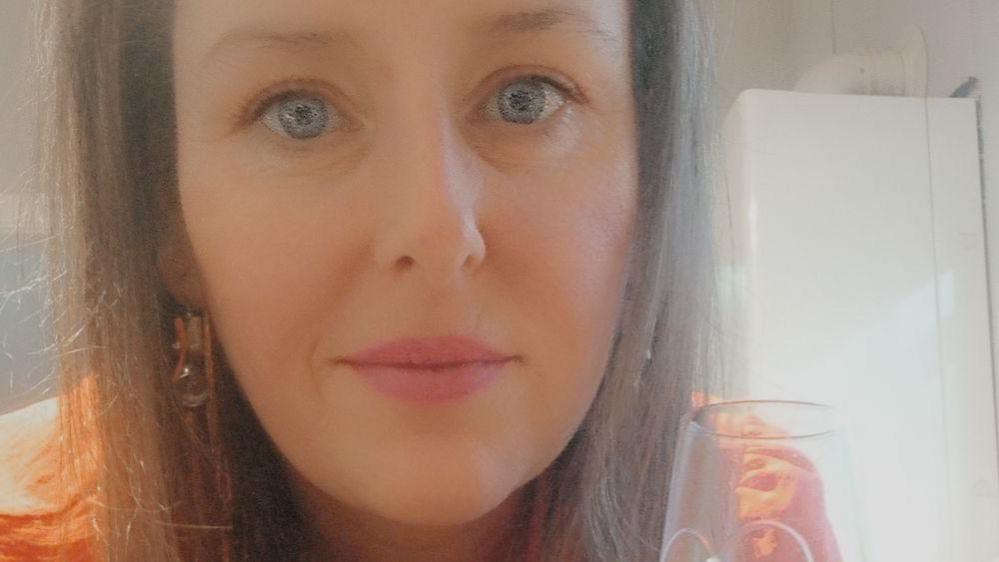 Close up image of a woman with long brown hair and blue eyes