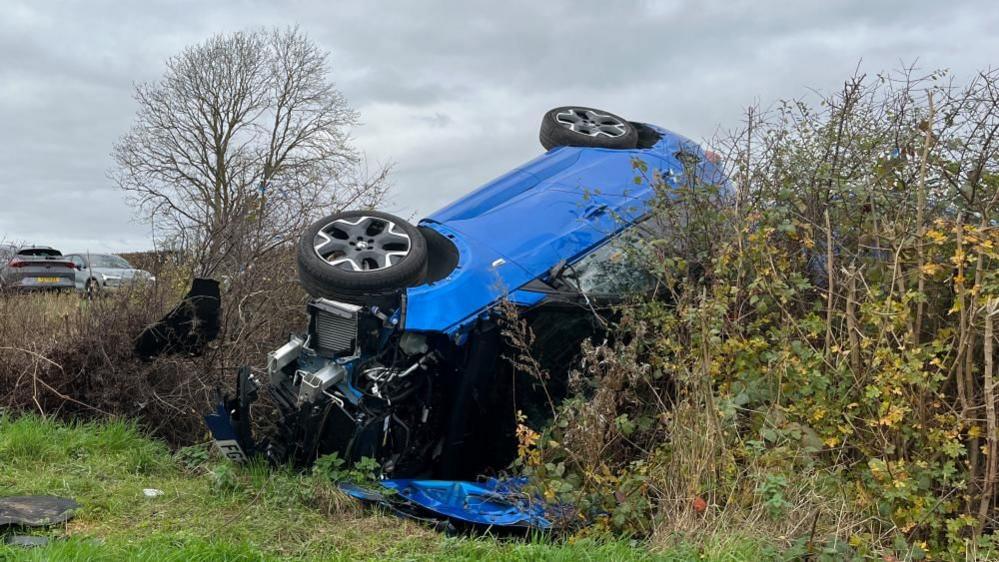 A blue crashed car on the side of the A617.