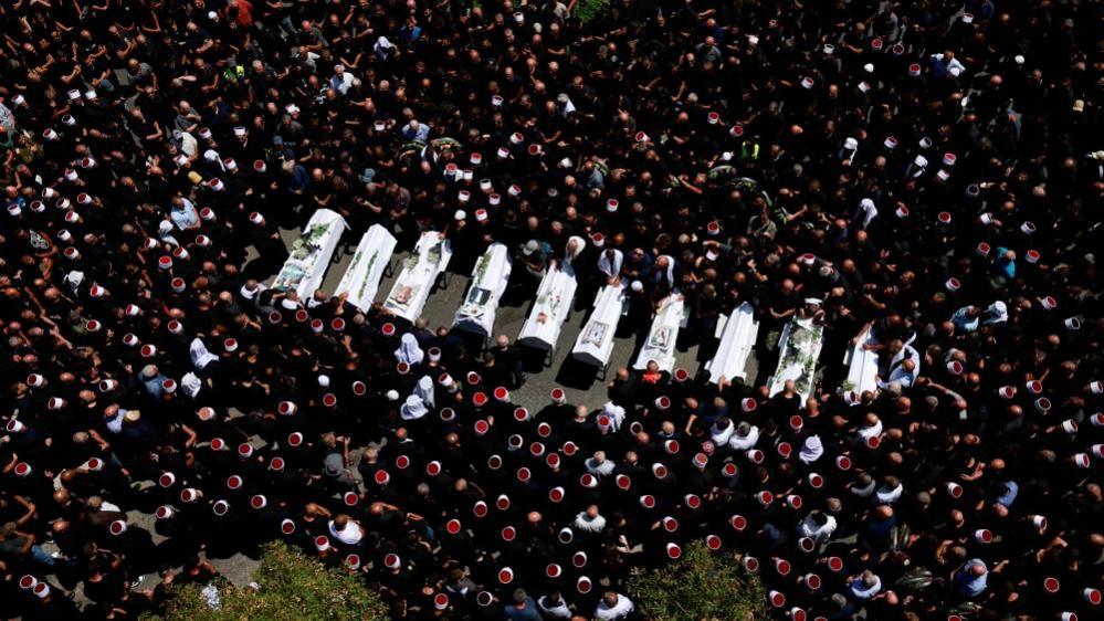 Mourners surround coffins in the streets