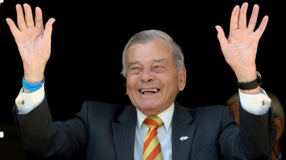 Dickie Bird smiles with his hands in the air.