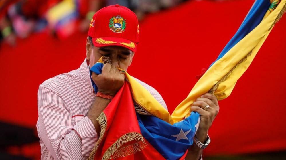 Venezuela's President Nicolas Maduro kisses a Venezuelan flag during a ceremony to swear in new community-based organisations
