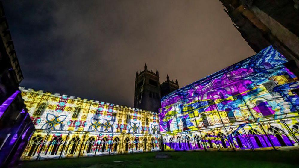 The exterior of Durham Cathedral lit up by a projection on Tuesday, 7 October 2025. The images are yellow and purple.