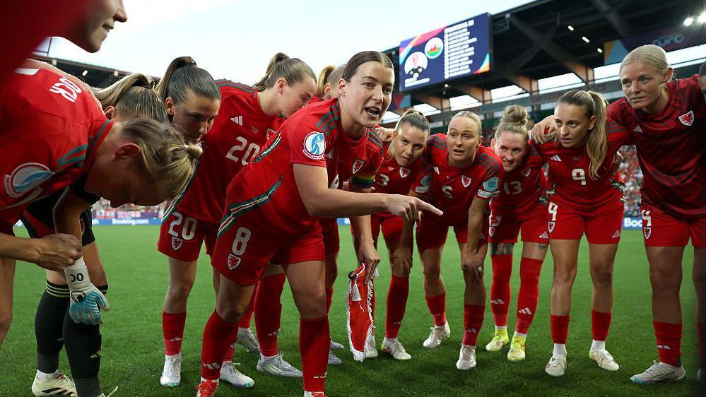 Wales women in an on-pitch huddle