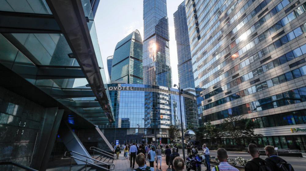 Crowds walk near a skyscraper in Moscow damaged by a drone attack