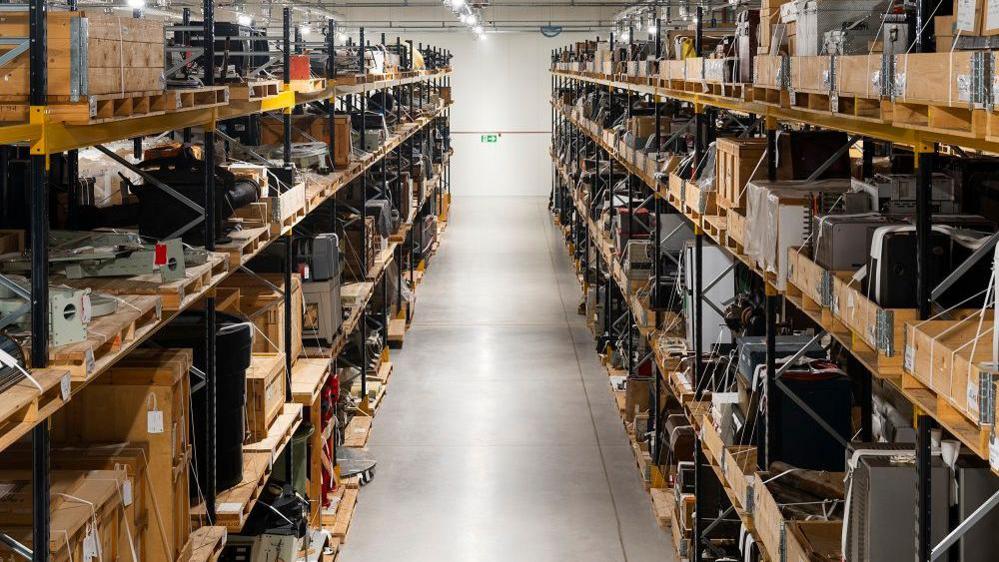 A view straight down the middle of pallet shelving full of old scientific equipment