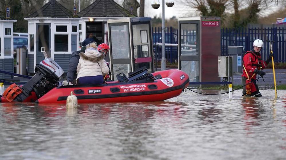 Person being rescued in a red inflatable boat at a mobile home site