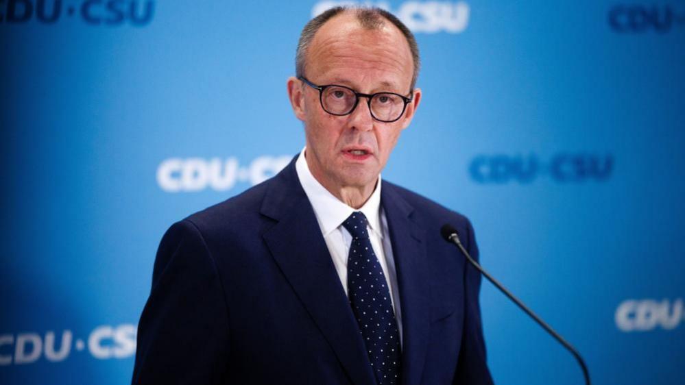 Friedrich Merz, the conservative opposition leader, talked to the media in a suit and tie a day after the knife attack in Bavaria