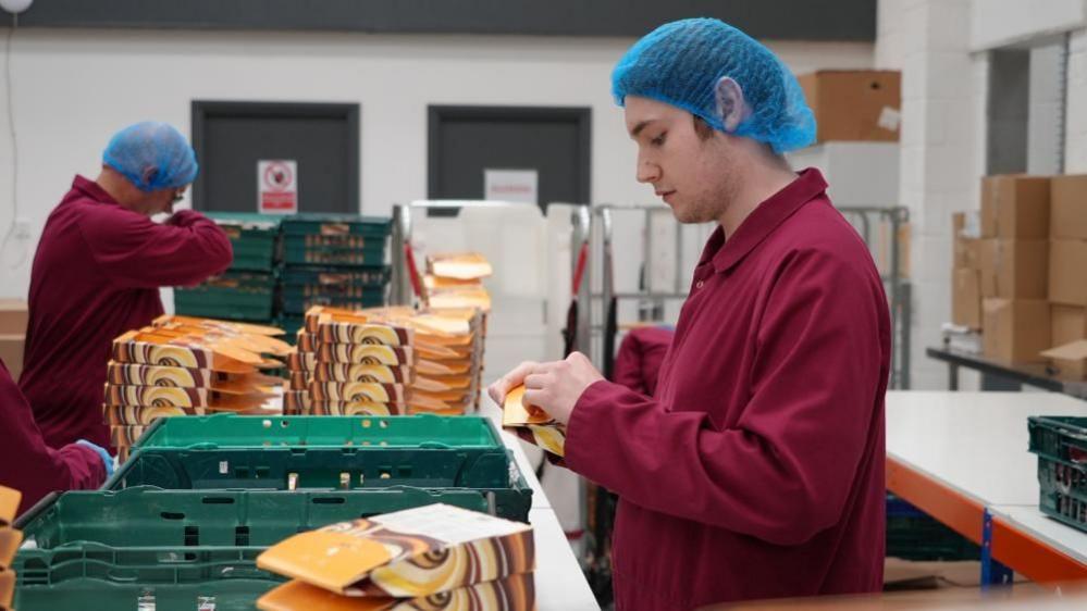 Factory workers package products at the Gnaw factory