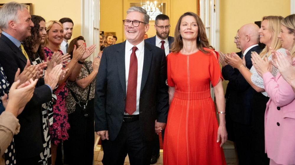 Keir Starmer and his wife Victoria Starmer are clapped in by staff as they enter his official London residence at No 10 Downing Street