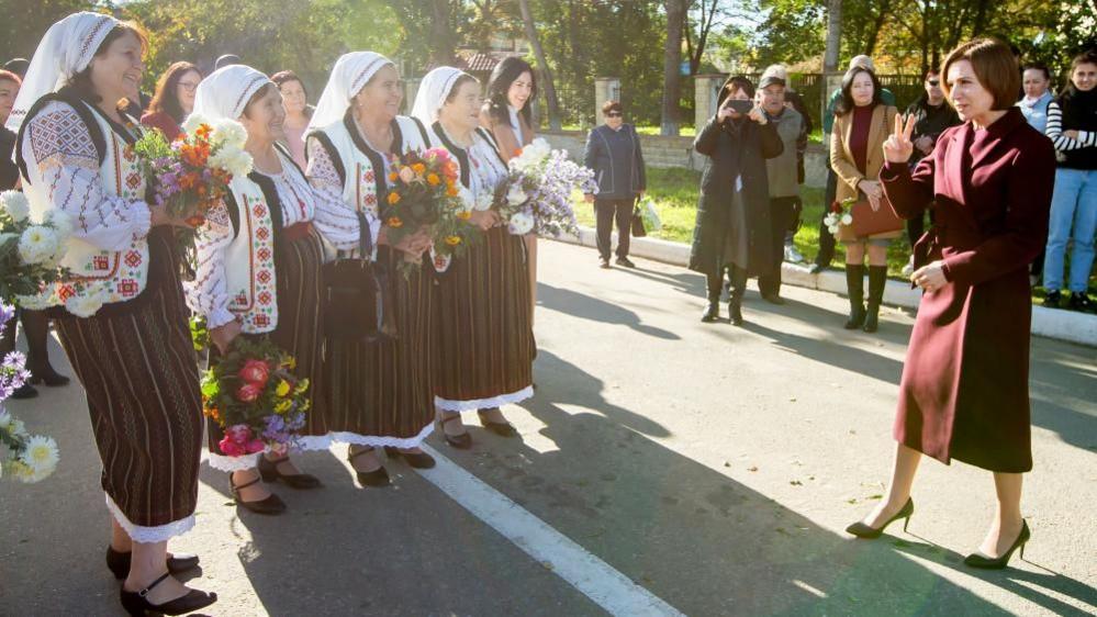 four women wearing traditional Moldovan dress welcomed President Maia Sandu at a campaign event on Friday in  Telenesti, 92 km north from Chisinau, Moldova