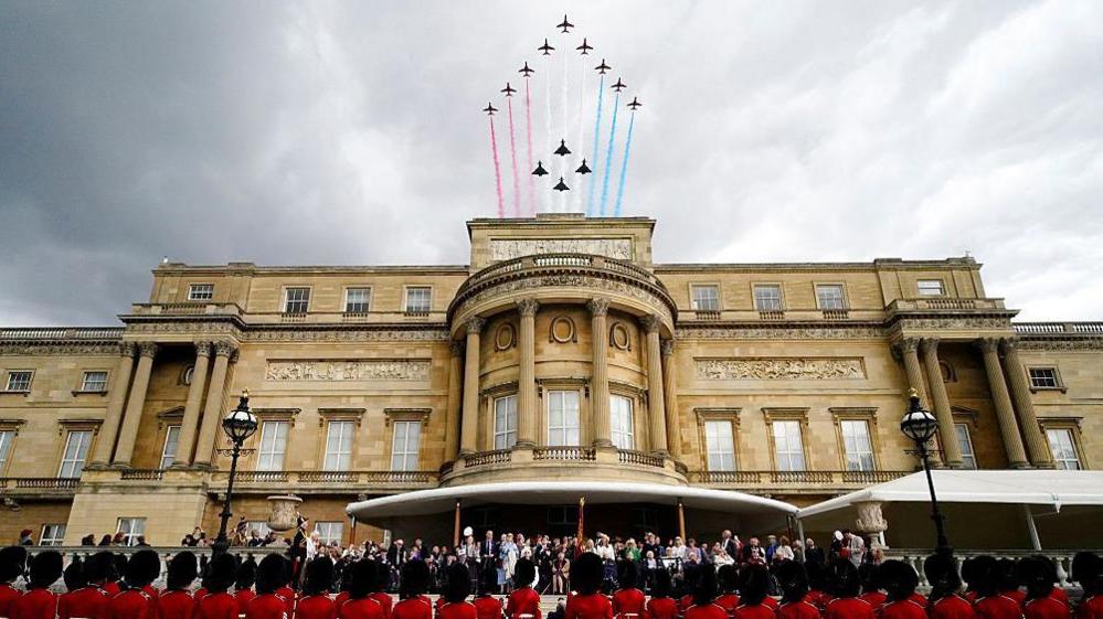 Veterans and members of the armed forces gather on the West Terrace in the gardens of Buckingham Palace to view the flypast