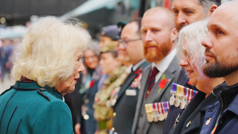 Queen Camilla, wearing a jade green jacket, speaking to armed service personnel