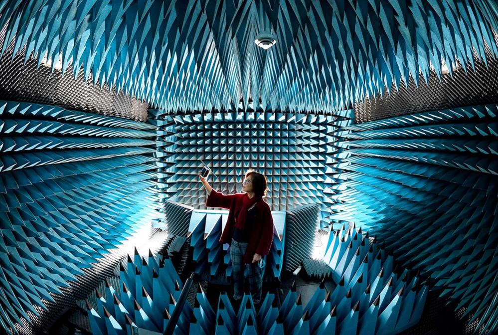 Professor Fun Hu inside Bradford University's "anechoic chamber", holding a "pocket cube" satellite