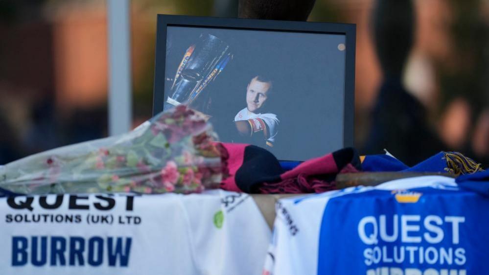 A bouquet of flowers next to a photo of Rob Burrow 