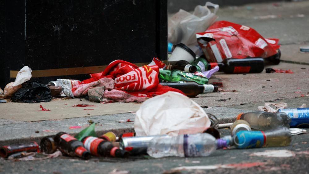 A Liverpool scarf and several empty bottles discarded on the ground