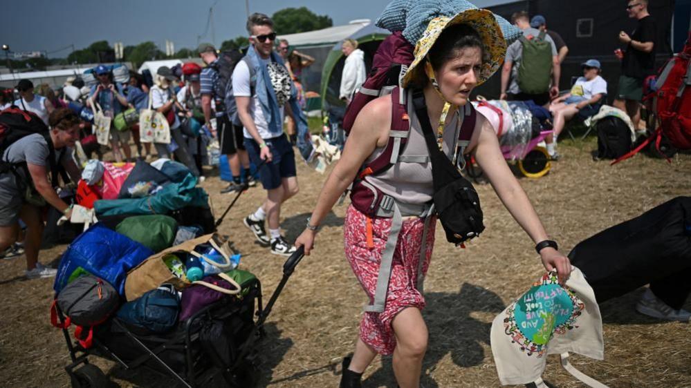 A woman arriving at Glastonbury with luggage