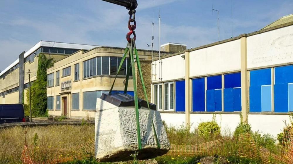 A crane moves a war memorial from outside the Cooper Tire and Rubber Company factory in Melksham, Wiltshire
