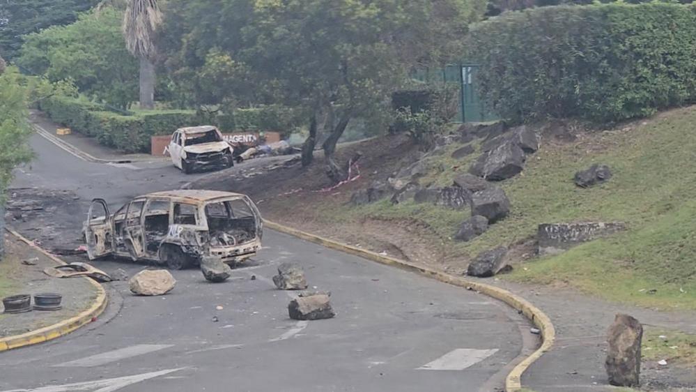 Two burnt out cars on a road