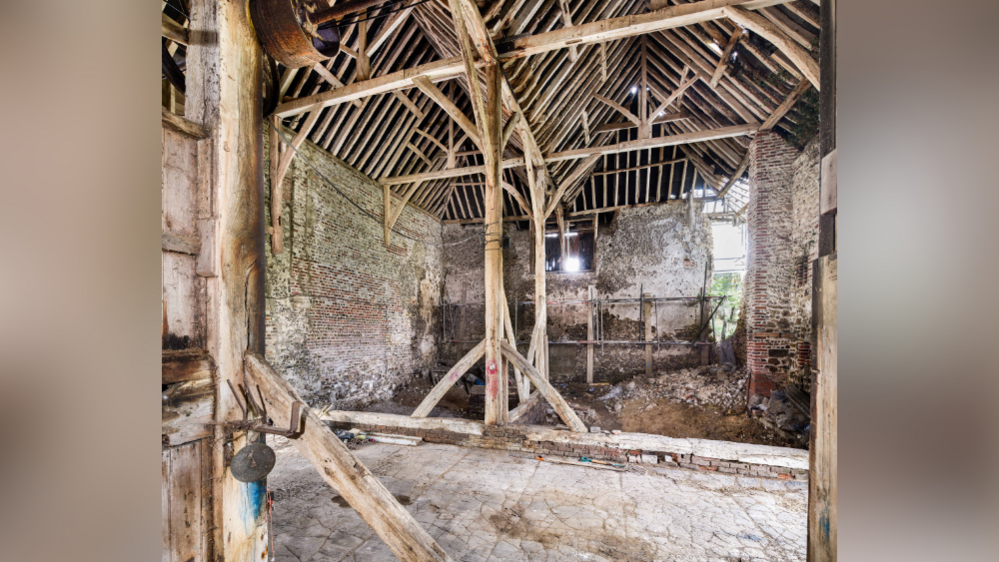 The inside of a medieval palace. The palace has aged wooden timbers, stone walls and a hole in the side of it.