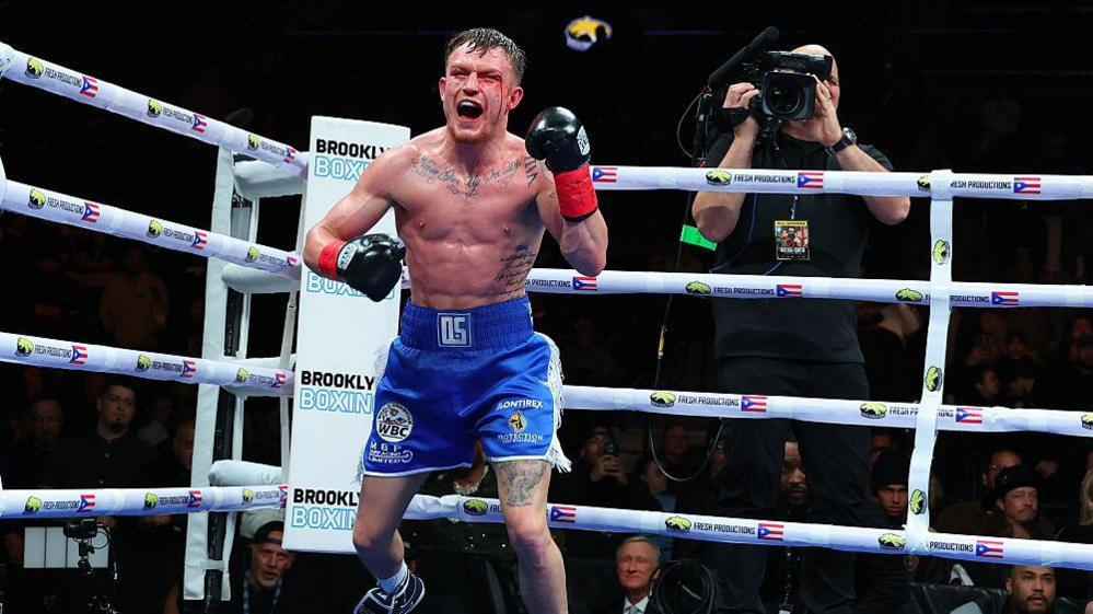 Dalton Smith, bloodied and cut on his face, celebrates in the ring